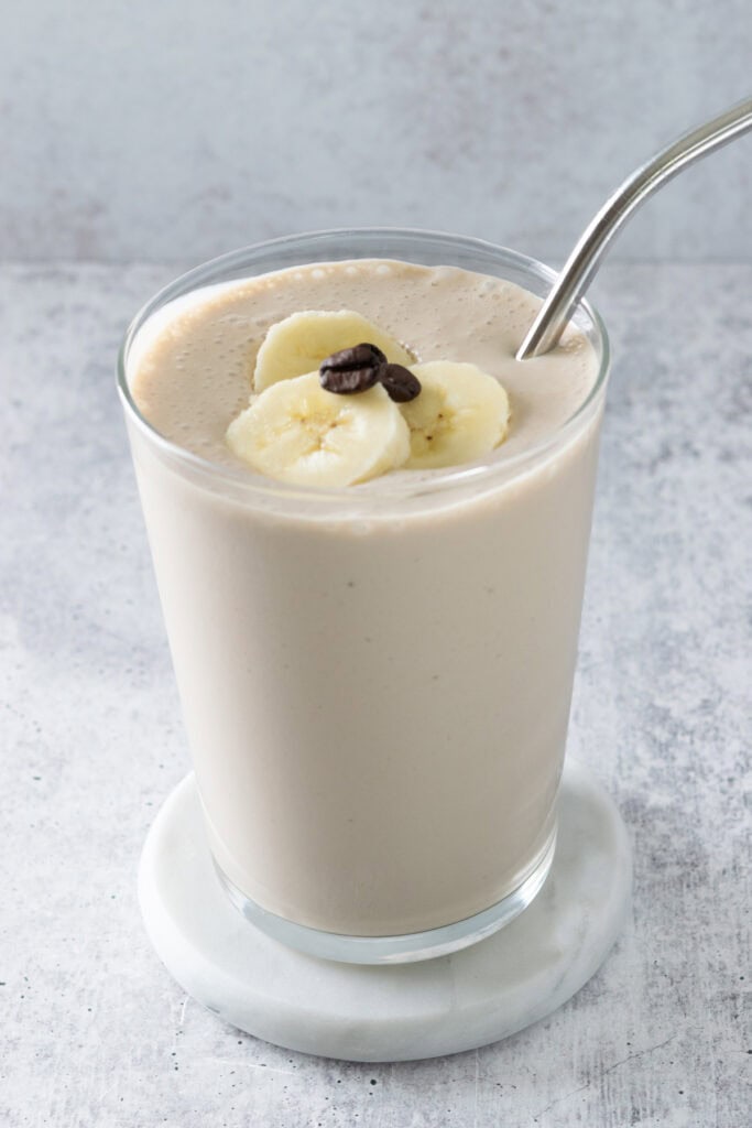 A coffee banana smoothie in a cup that shows how rich and creamy it is.
