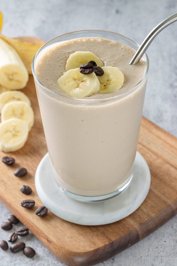 Homemade coffee banana smoothie topped with slices of banana and a few coffee beans.