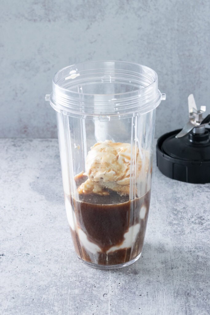Cold brew coffee concentrate and vanilla ice cream in a blender container.