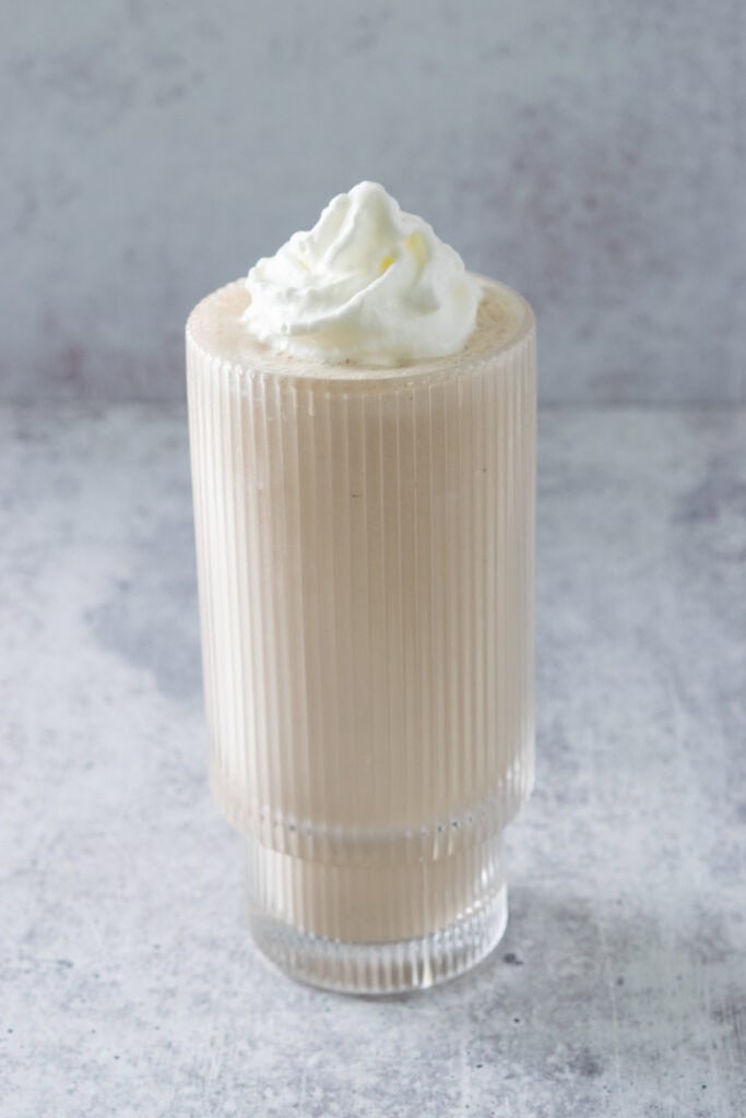 Homemade coffee milkshake served in a tall glass with whipped cream on top.