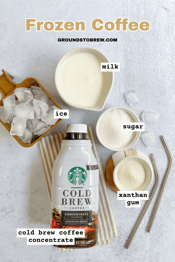 Overhead picture of ingredients needed to make a homemade frozen coffee, including ice cubes, pitcher of milk, bowl of sugar, bowl of xanthan gum and bottle of Starbucks cold brew coffee concentrate.