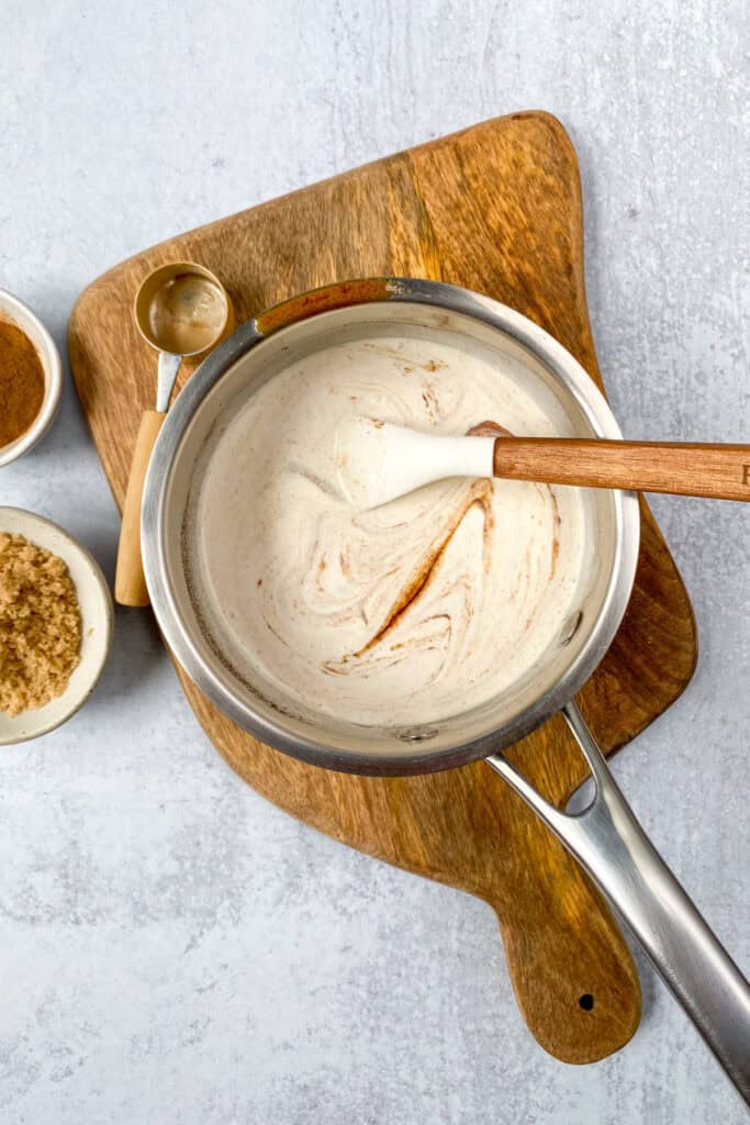 Cream being stirred in saucepan with cinnamon roll flavored syrup.