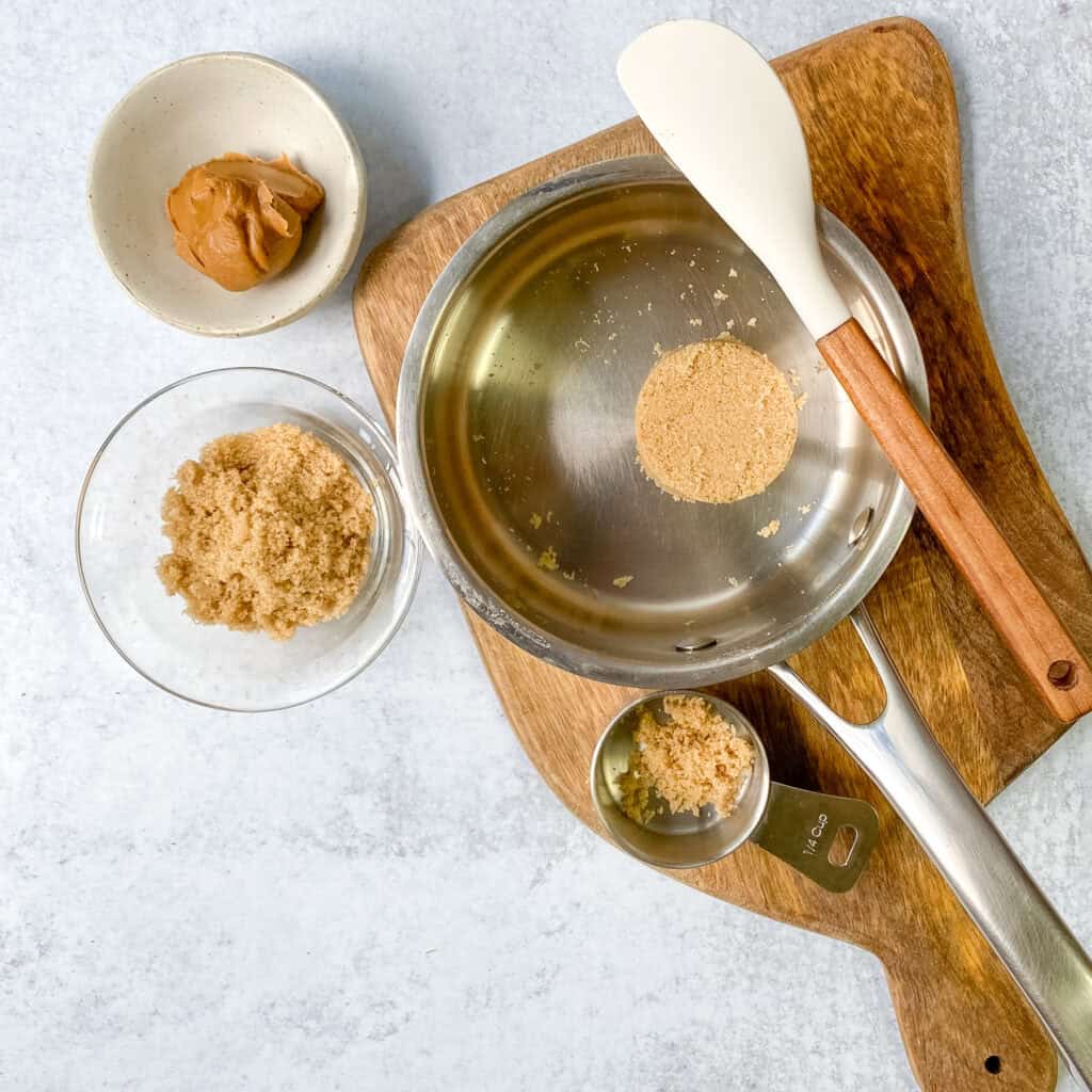 Overhead picture with brown sugar in a small saucepan next to a small bowl of brown sugar and another with cookie butter spread in it.