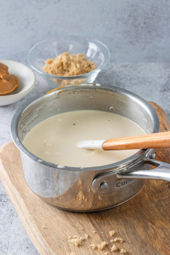 Homemade cookie butter creamer in a saucepan with a rubber spatula in it.