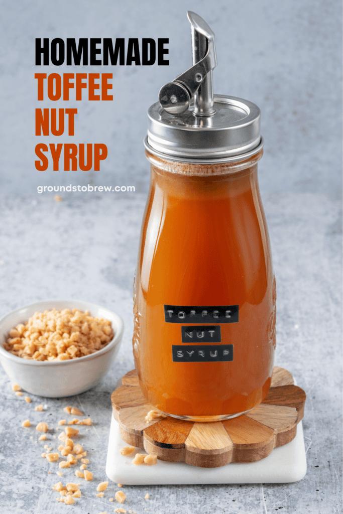 Pinterest pin for homemade toffee nut syrup recipe showing a bottle of the syrup and a bowl of toffee bits.