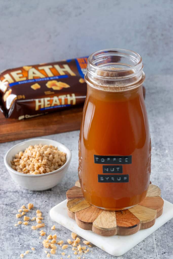 Toffee nut syrup in a glass bottle next to a bag of Heath English toffee bits.