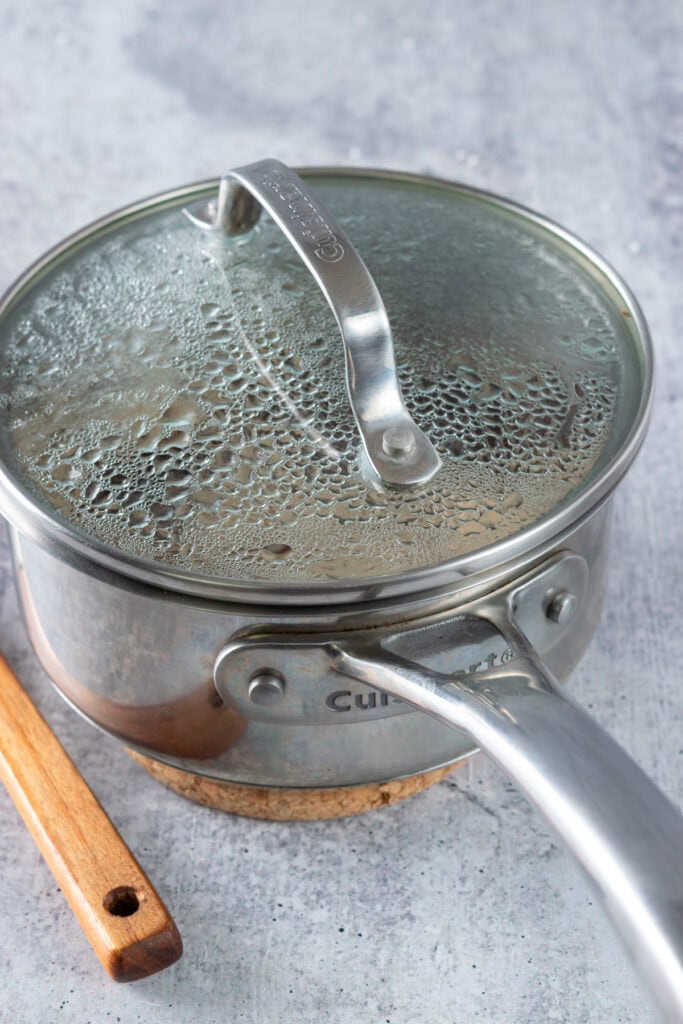 Simmering homemade toffee nut syrup in a saucepan with the lid on.